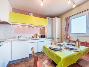 Une cuisine compacte avec un coin repas, comprenant un évier, une machine à café et une table dressée pour quatre personnes.