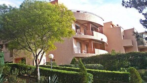 A multi-story residential building with balconies, surrounded by well-maintained hedges and a tree. - Le Grand Vallon by Interhome (Bandol)
