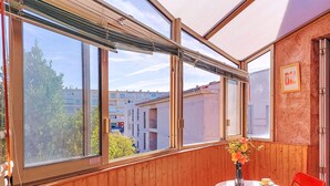 A balcony with wooden paneling, a round table with two chairs, and a vase with flowers. - Le Grand Vallon by Interhome (Bandol)