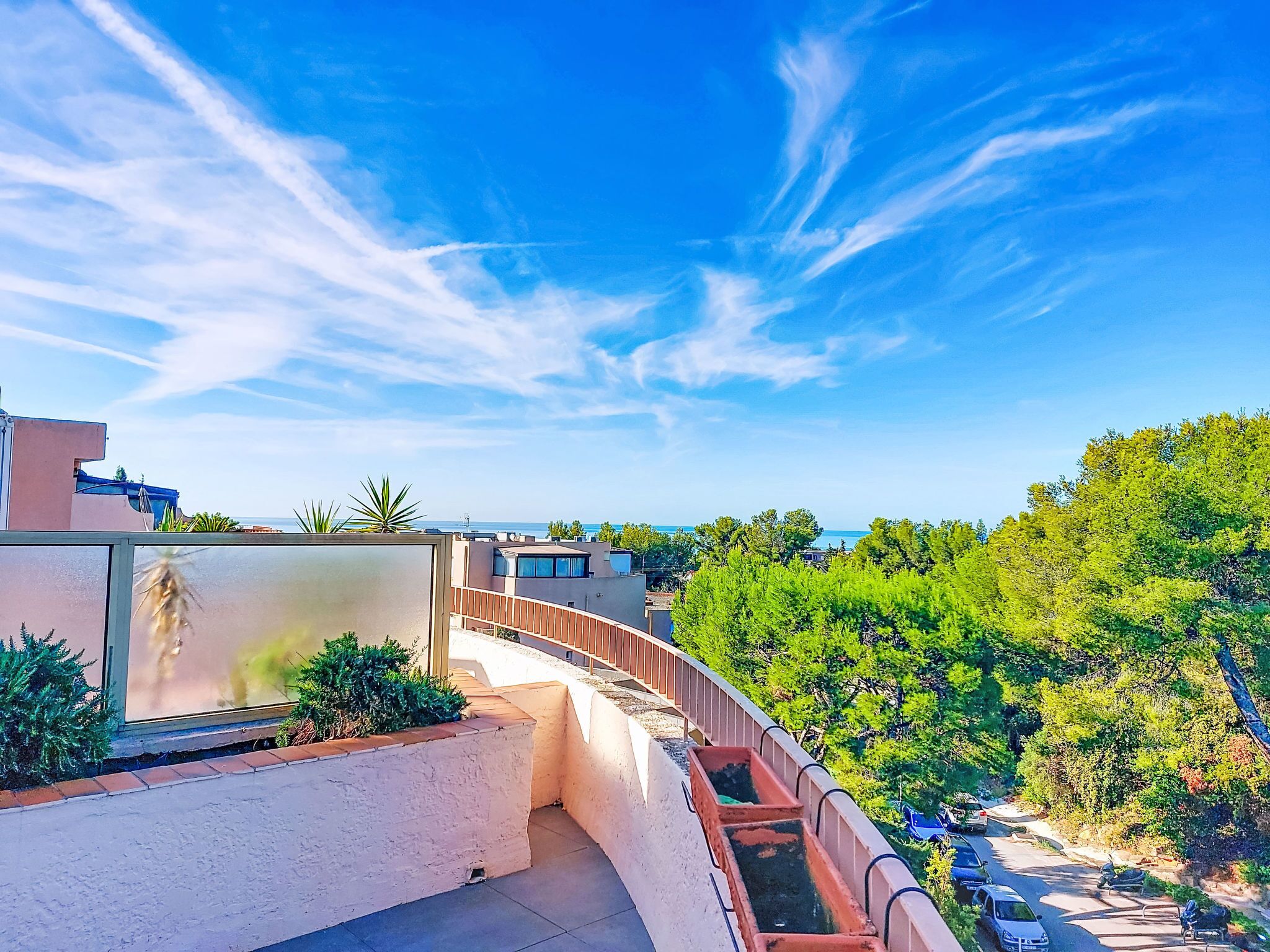 A balcony with a view of the sea and trees.