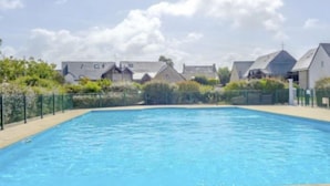 A rectangular swimming pool with a tiled edge, surrounded by a low fence and greenery. - Les Reflets de Carnac by Interhome (Carnac)