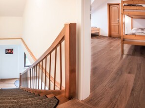 Una escalera con barandillas de madera que conduce a un dormitorio con literas.