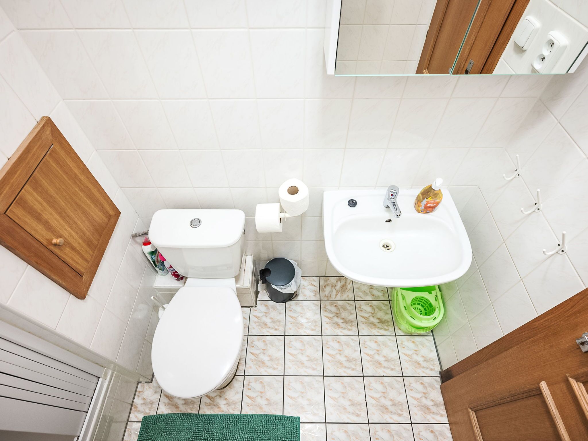 Une salle de bain avec des toilettes, un lavabo et une poubelle verte.