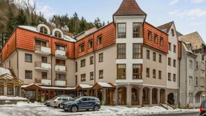 A multi-story hotel with a red-tiled roof, multiple balconies, and a central tower. - Lanovka by Interhome (Jachymov)