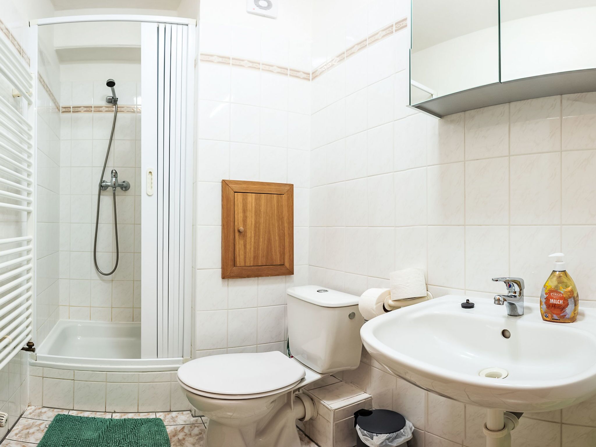 A bathroom with a shower, toilet, sink, and a cabinet.