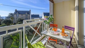 A balcony with a table set for breakfast, a chair, and a vase of flowers. - Les Villas de Kermaria by Interhome (Quiberon)