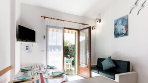 A modern living room with a dining area, a television, and a sliding glass door leading to an outdoor patio. - Plage sud by Interhome (Capbreton)