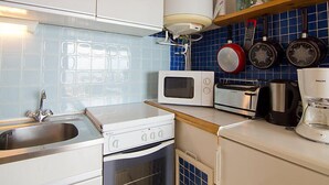 Cocina compacta con lavamanos, estufa, microondas, tostadora y cafetera.
