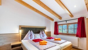 A double bed with a wooden headboard, two pillows, and a bedside table. - Mooslehen by Interhome (Kaprun)