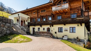 A traditional wooden chalet with a balcony, stone staircase, and a paved driveway. - Mooslehen by Interhome (Kaprun)