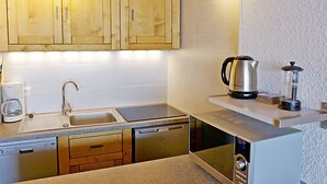 Een moderne keuken met houten kastjes, een roestvrijstalen spoelbak, een koffiezetapparaat, een waterkoker, een blender en een magnetron.