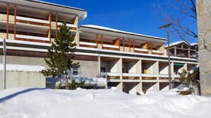 Un edificio moderno con varios pisos y balcones, rodeado de nieve.