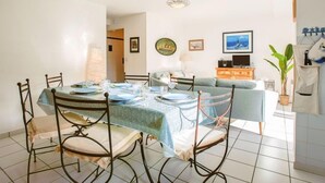 A dining area with a round table set for four, surrounded by metal chairs. There is a sofa and a television in the background. - Le Parc des Druides by Interhome (Carnac)
