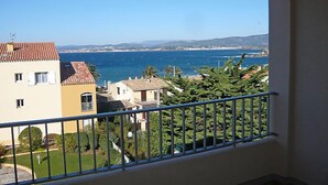 Un balcón con vista a una zona costera, que incluye edificios y vegetación.