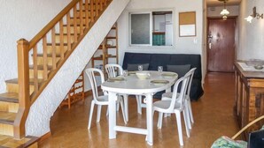 Un comedor con una mesa redonda, sillas blancas y una escalera de madera.