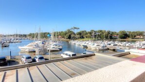 A marina with multiple boats docked, a parking area with cars, and a clear blue sky. - Le Grand Pavois by Interhome (Capbreton)