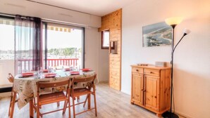 A dining area with a table set for four, a wooden cabinet, and a floor lamp. - Le Grand Pavois by Interhome (Capbreton)
