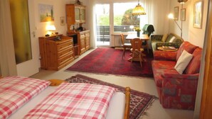 A cozy room with a bed, a sofa, a dining table, and a kitchen area. - Fellhornstrasse by Interhome (Oberstdorf)