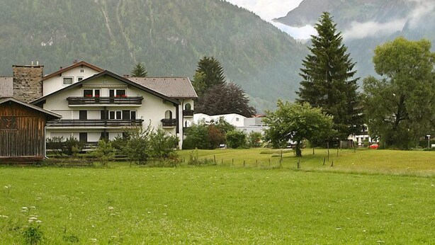 A two-story building with a balcony, surrounded by a grassy field and mountains in the background. - Fellhornstrasse by Interhome (Oberstdorf)