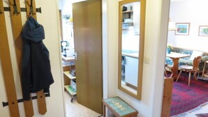 A hallway with a coat rack, a wooden bench, a mirror, and a door leading to a room with a desk and shelves. - Fellhornstrasse by Interhome (Oberstdorf)