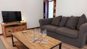 A living room with a wooden coffee table, grey sofa, and a TV on a wooden stand. - Le Sporting by Interhome (Saint Gervais)
