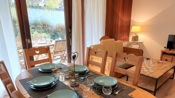 A dining area with a round table set for four, surrounded by wooden chairs. - Le Sporting by Interhome (Saint Gervais)