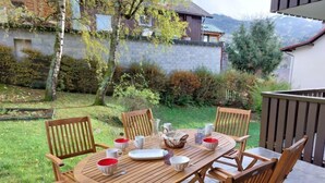 A wooden table and chairs set outdoors with a view of a house and trees in the background. - Le Sporting by Interhome (Saint Gervais)