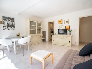A modern living room with a dining area, a sofa, a TV, and a cabinet.