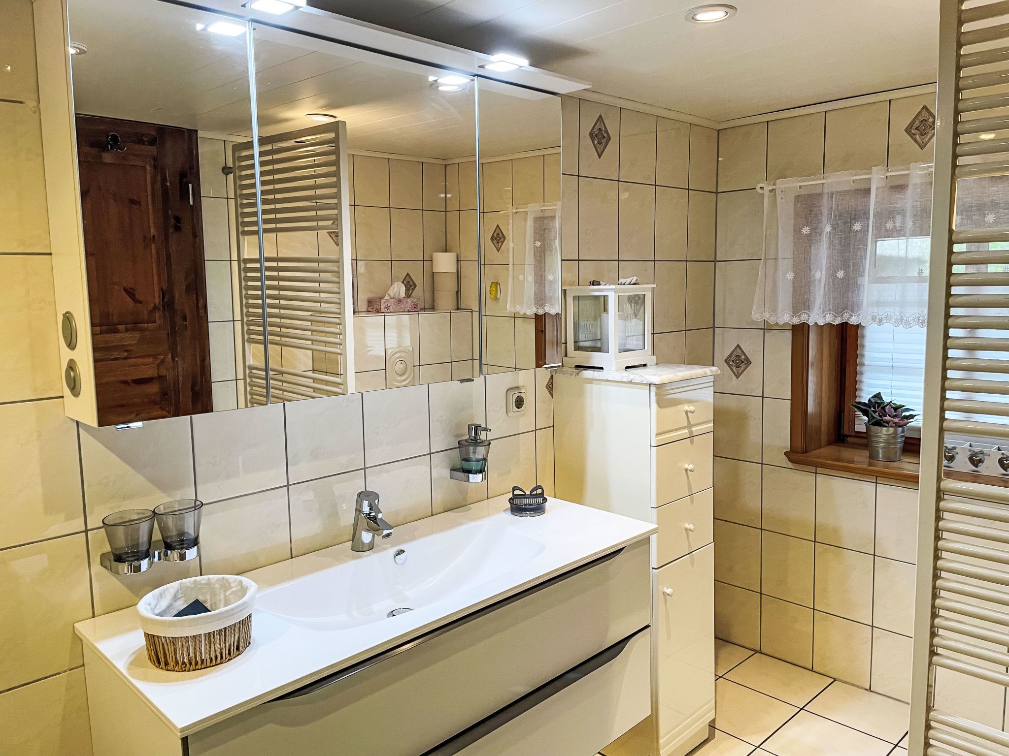 Une salle de bain moderne avec un grand miroir, un lavabo blanc et un meuble-lavabo doté de tiroirs.