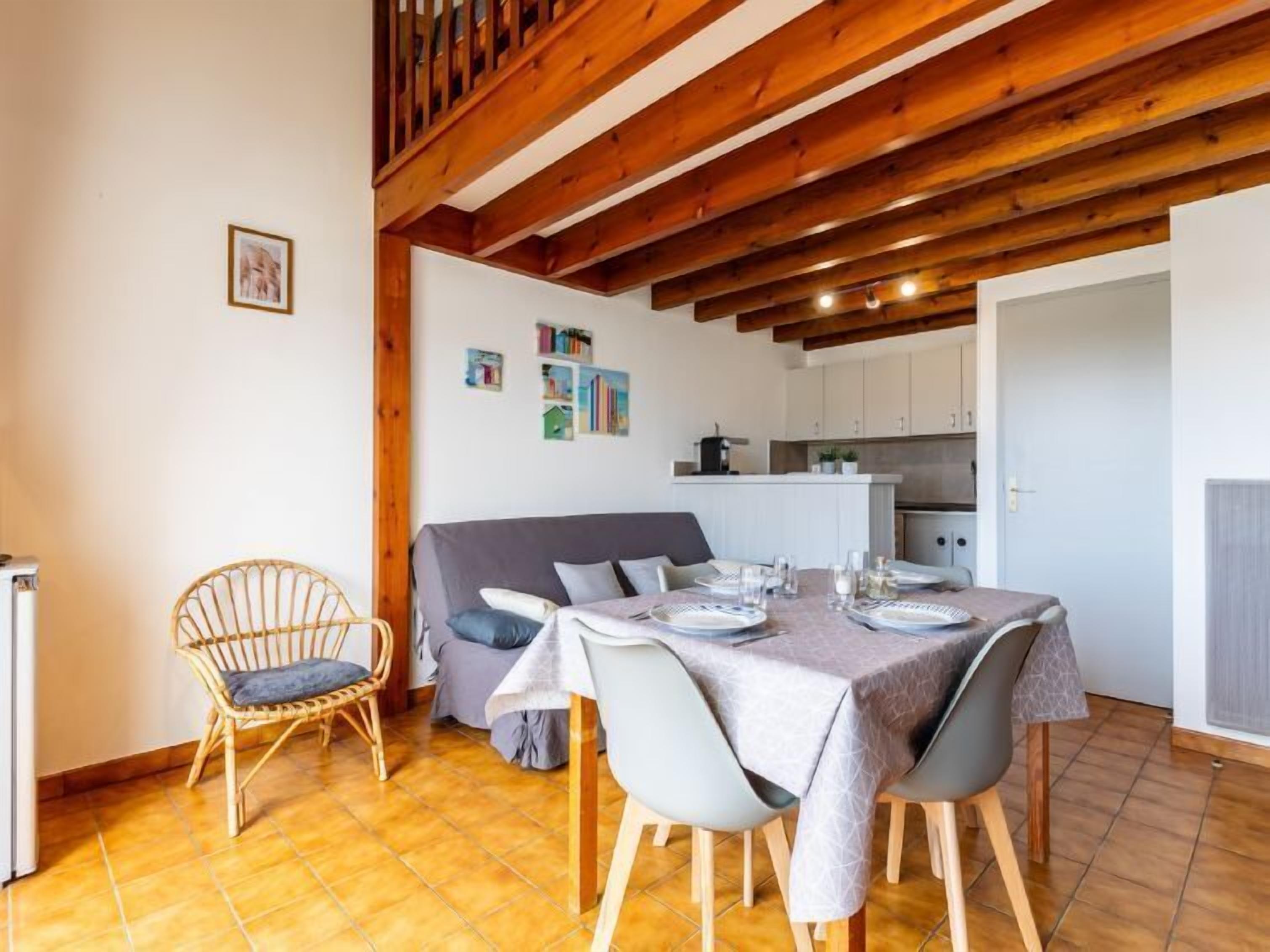 A dining area with a table set for four, a sofa, and a wicker chair.