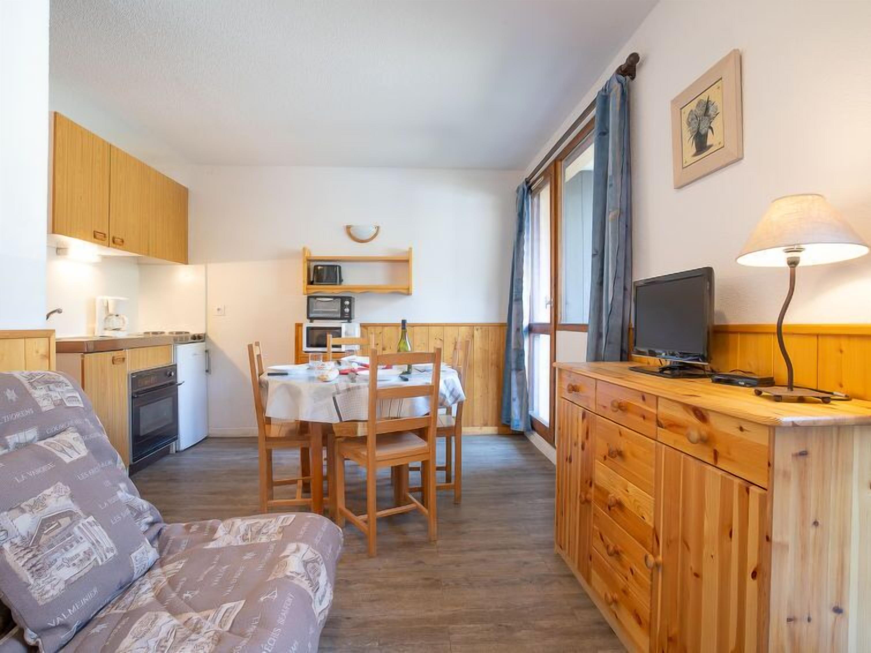 Un espacio habitable compacto con kitchenette, comedor y televisor.