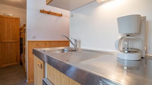 A modern kitchen with a stainless steel sink, wooden cabinets, and a coffee maker. - Sarvan 315 by Interhome (Les Menuires)