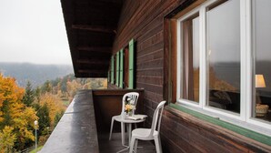 En træhytte med balkon med udsigt over en skovdal.