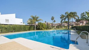 A swimming pool with a clear blue water, surrounded by palm trees and a white building. - Brisamar - Novo Sancti Petri by Interhome (Chiclana de la frontera)
