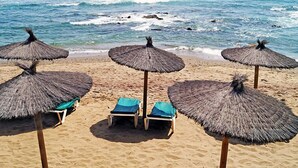 A beach with thatched umbrellas and lounge chairs, a sandy shore, and the ocean in the background. - Dona Lola by Interhome (Calahonda)