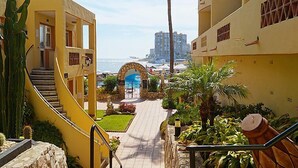 A hotel corridor with a view of the ocean, a palm tree, and a staircase leading to a pool area. - Dona Lola by Interhome (Calahonda)