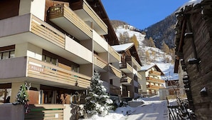 A multi-story hotel with balconies, a snow-covered ground, and a mountainous backdrop. - Castor und Pollux by Interhome (Täsch)