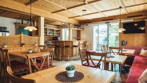 A cozy, wooden-furnished restaurant with multiple seating areas, including tables and a sofa. - Apartment Ladis by Interhome (Fiss)