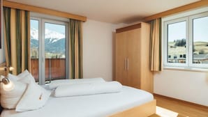 A modern bedroom with a wooden bed, large windows, and a view of mountains. - Apartment Ladis by Interhome (Fiss)