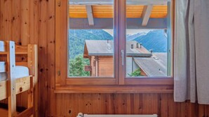 Una cabaña de madera con un ventanal que ofrece vistas a la montaña.