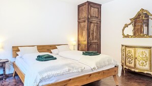 Un lit en bois avec une literie blanche, une grande armoire en bois et un miroir avec un cadre doré.