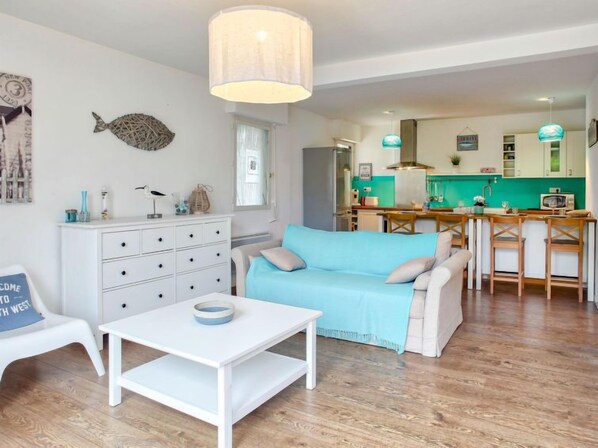 Een moderne woonkamer met een bank, een salontafel en een eethoek, met een keuken op de achtergrond.