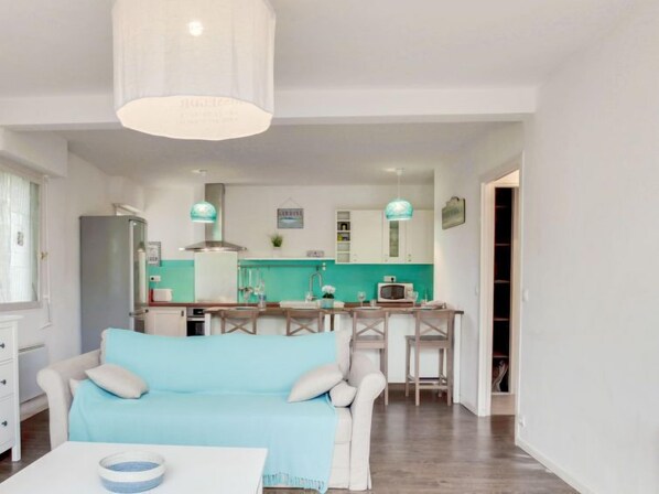 A modern living room with a sofa, a dining table, and a kitchen area in the background. - Cantegrit by Interhome (Capbreton)