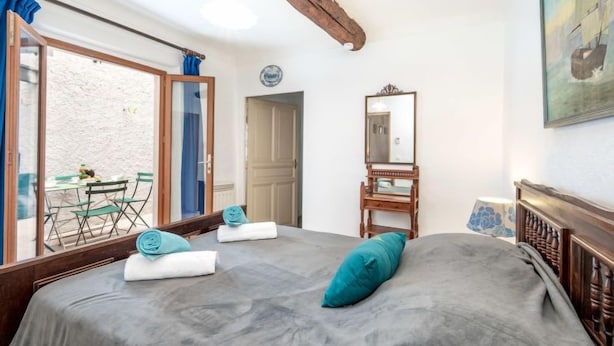 A bedroom with a bed, a wooden headboard, a mirror, and a window with curtains. - Rue de la Pompe by Interhome (Antibes)