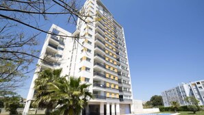 A high-rise residential building with multiple balconies, a swimming pool, and a well-maintained lawn with palm trees. - Costa Calpe by Interhome (Calpe/Calp)