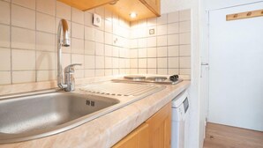 Une cuisine dotée d’un évier en acier inoxydable, de meubles en bois et d’un dosseret de carrelage blanc.