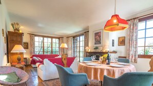 Un coin repas avec une table dressée pour quatre personnes, entourée de chaises, et un canapé en arrière-plan.