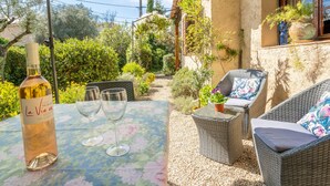 Une terrasse extérieure avec une table dressée pour deux personnes, une bouteille de vin et deux verres.