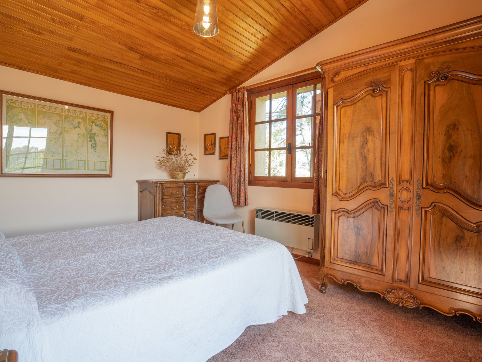 Une chambre à coucher avec un grand lit, une armoire en bois et un bureau avec une chaise.