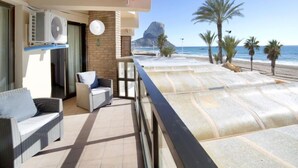 A balcony with a view of the beach, a chair, a table, and an air conditioning unit. - Calpemar by Interhome (Calpe/Calp)